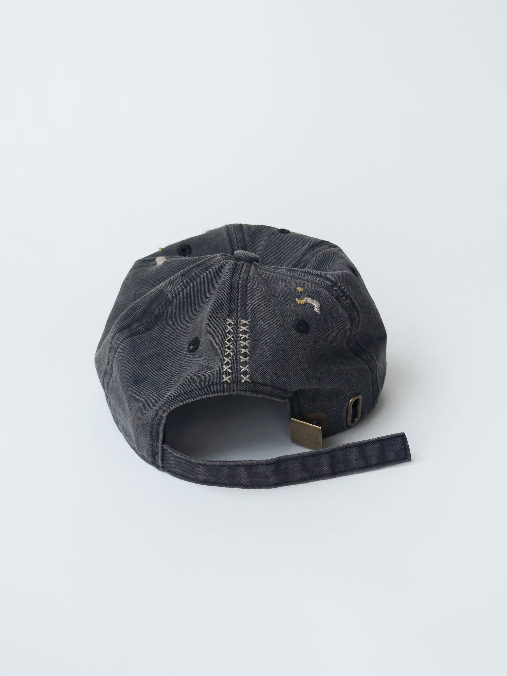 La casquette washed black d'objet, hand embroidered, frayed, back picture with M signature logo.