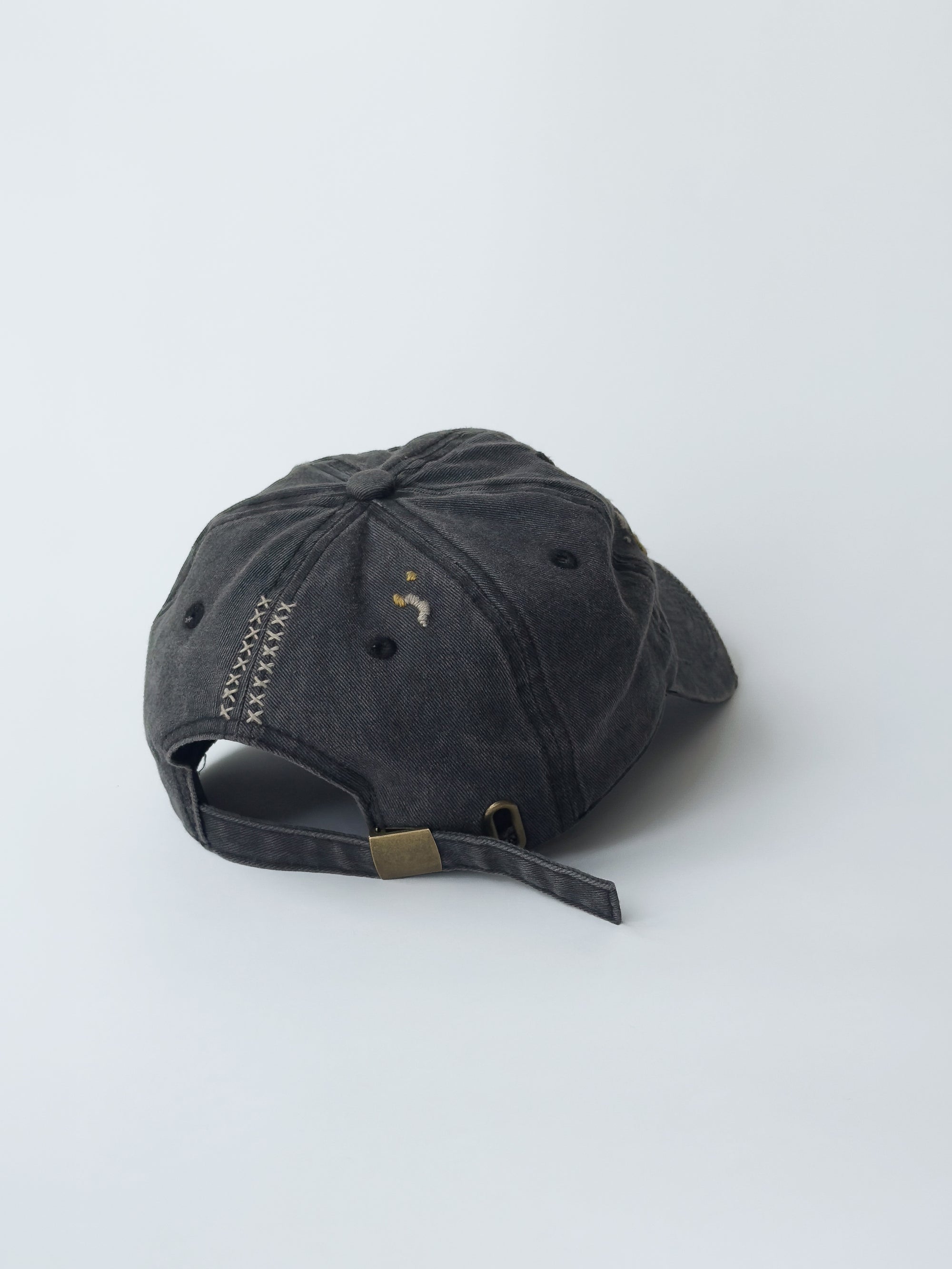 La casquette washed black d'objet, hand embroidered, frayed, 3/4 back picture with M signature logo.
