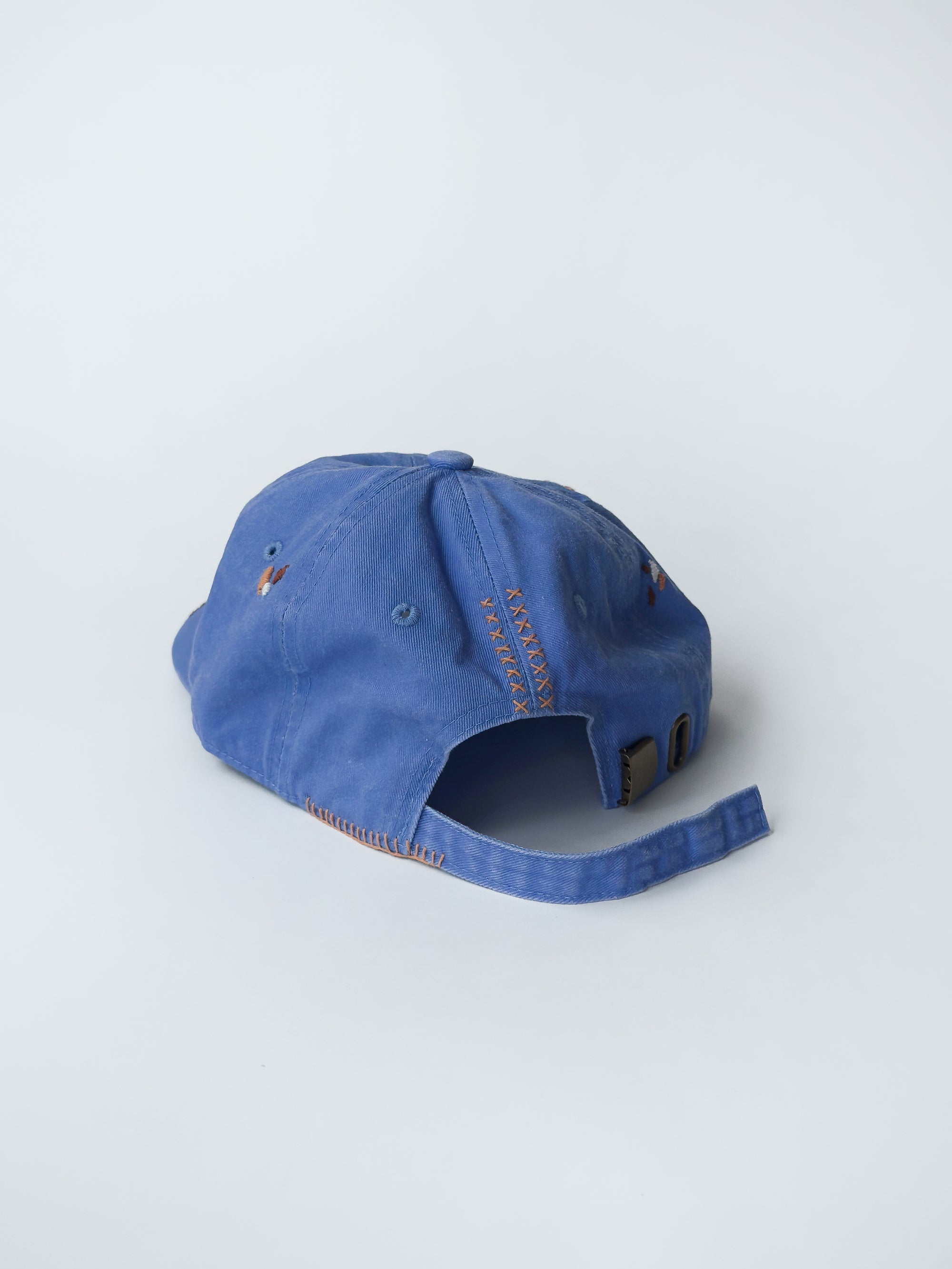 La casquette washed blue d'objet, hand embroidered, frayed, back picture, with brown and orange thread.